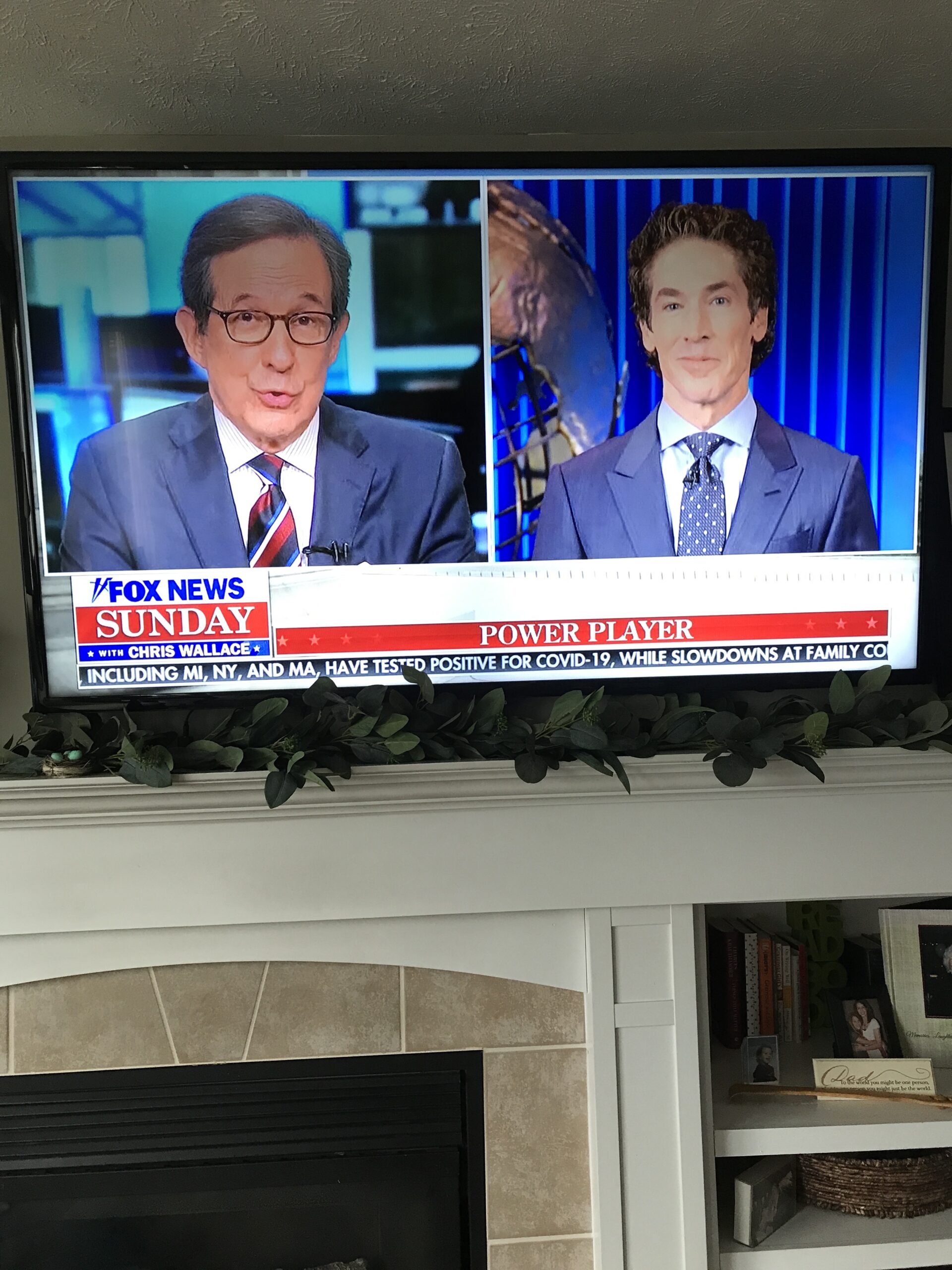 Wall mounted television over fireplace, showing Chris Matthews and Joel Osteen on Fox News